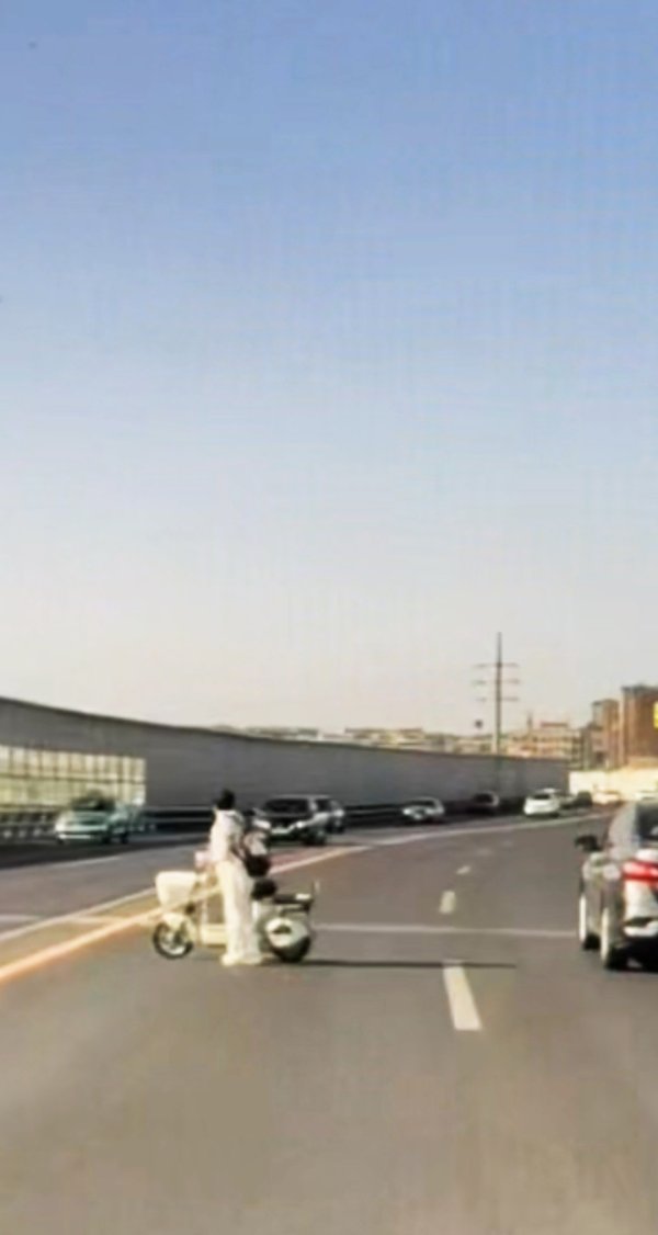 太危险！女子推电动车横穿东联路高架桥
